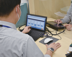 タブレット端末でスムーズに手続きが出来る（手前は職員側）